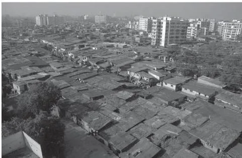 A narrow lane inside Dharavi, the so-called ninety-foot road reduced to less than half its width, showing the crowding of the slum