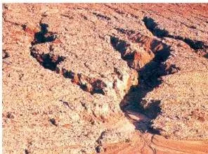 Resources and Development Class 10: NCERT Chapter 1 with PDF Photograph of gully erosion showing deep channels cut into the land by running water, forming bad land