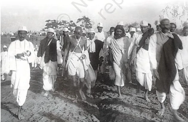 Mahatma Gandhi walking at the head of the Dandi March with a column of satyagrahis following him along the road
