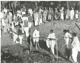 Mahatma Gandhi walking along a road on his way to a riot-torn area during the Partition violence